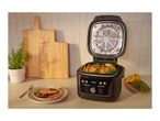 A multi-cooker with salmon and vegetables on a kitchen counter next to a plated meal.