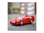 Red toy sports car on a dark surface with a blurred background.