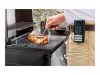 Man grilling meat with a digital thermometer clipped to his belt.