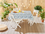 Garden table with floral tablecloth, white folding chairs, and green plants.