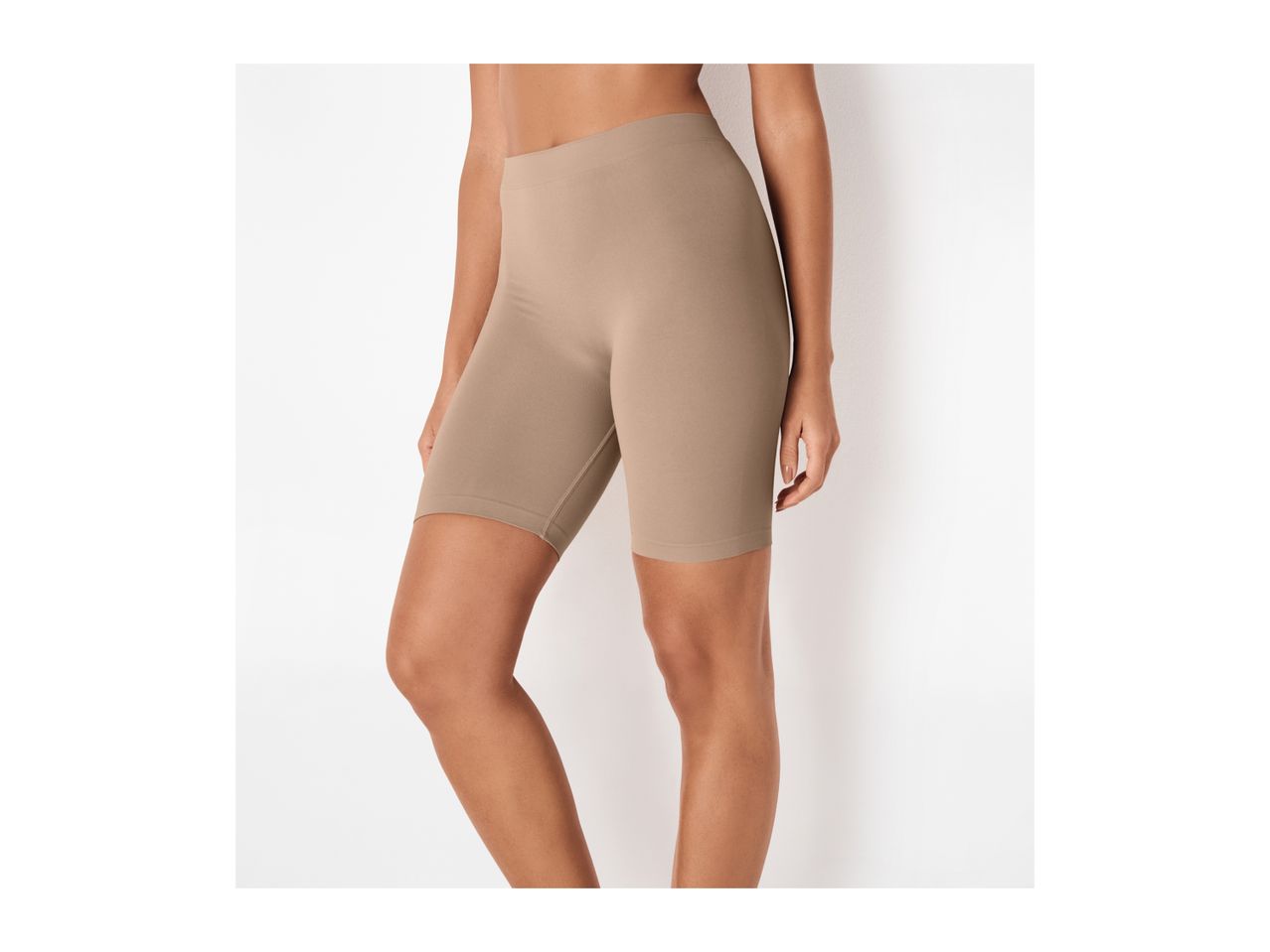 Woman wearing seamless beige cycling shorts, side view.