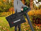 A person using a Parkside leaf blower with a collection bag in an autumn yard.