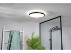 Um elegante lustre de teto redondo preto ilumina um banheiro moderno.
