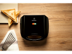 Sandwich-uri triunghiulare prăjite lângă un toaster SilverCrest negru pe o masă din lemn.