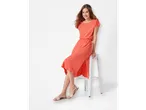 Femeie purtând o rochie midi coral și sandale bej.