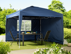 A navy blue pop-up gazebo with side panels provides shade for a patio table and chairs in a garden setting.