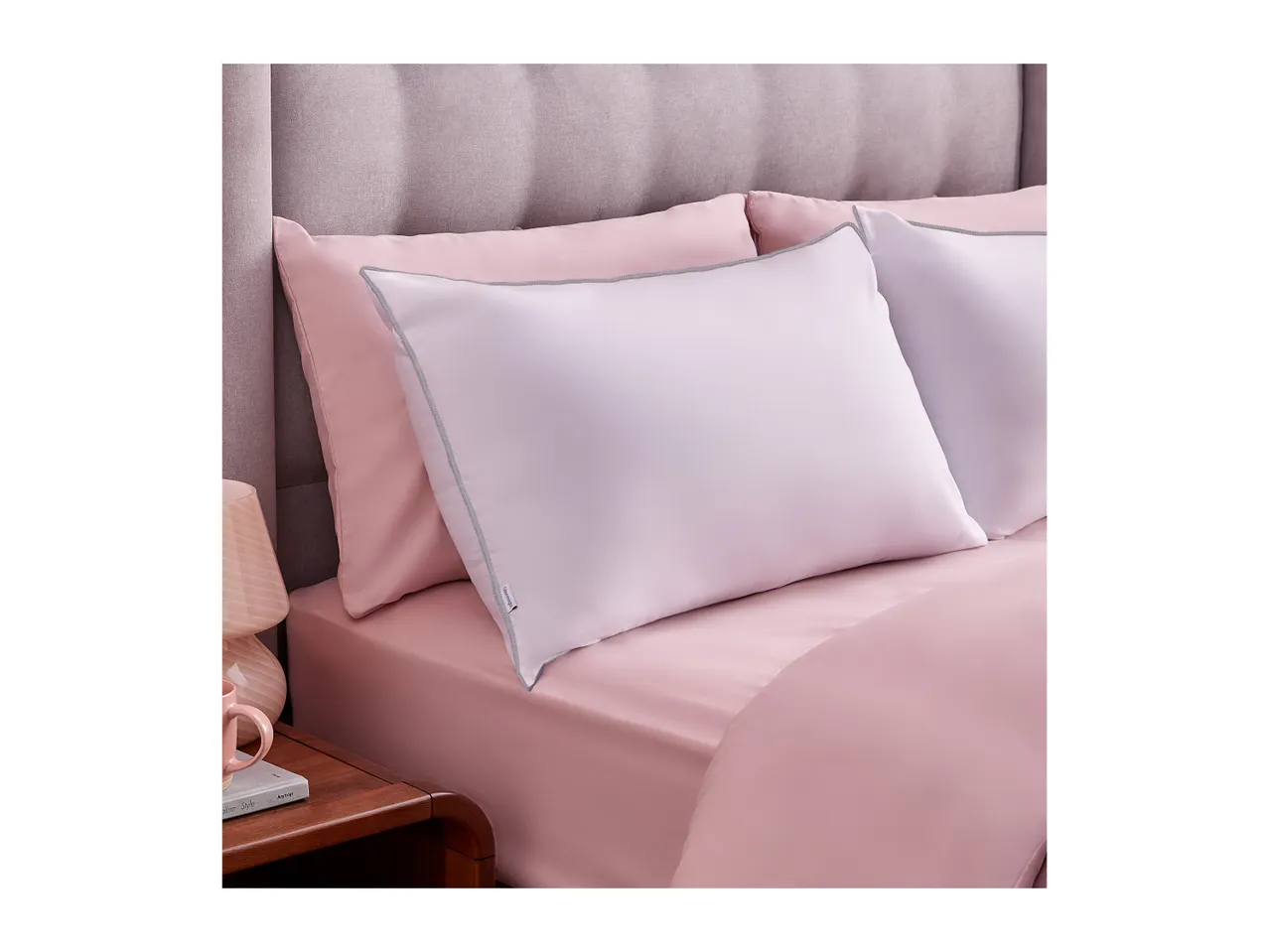 Pink bed with a light purple pillow and a wooden nightstand