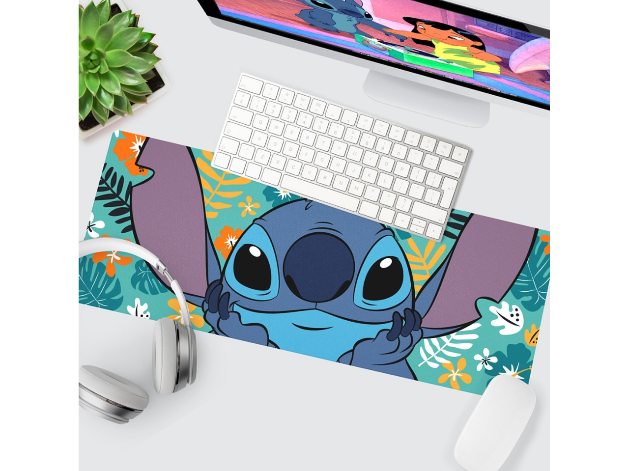 Desk mat with Stitch design, keyboard, mouse, headphones, plant, and monitor
