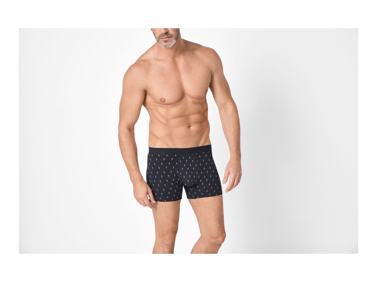 Man in navy blue boxer briefs with white anchor print, standing against a white background.