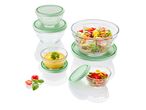 Glass mixing bowls and storage containers with pastel green lids, filled with various salads and dips.