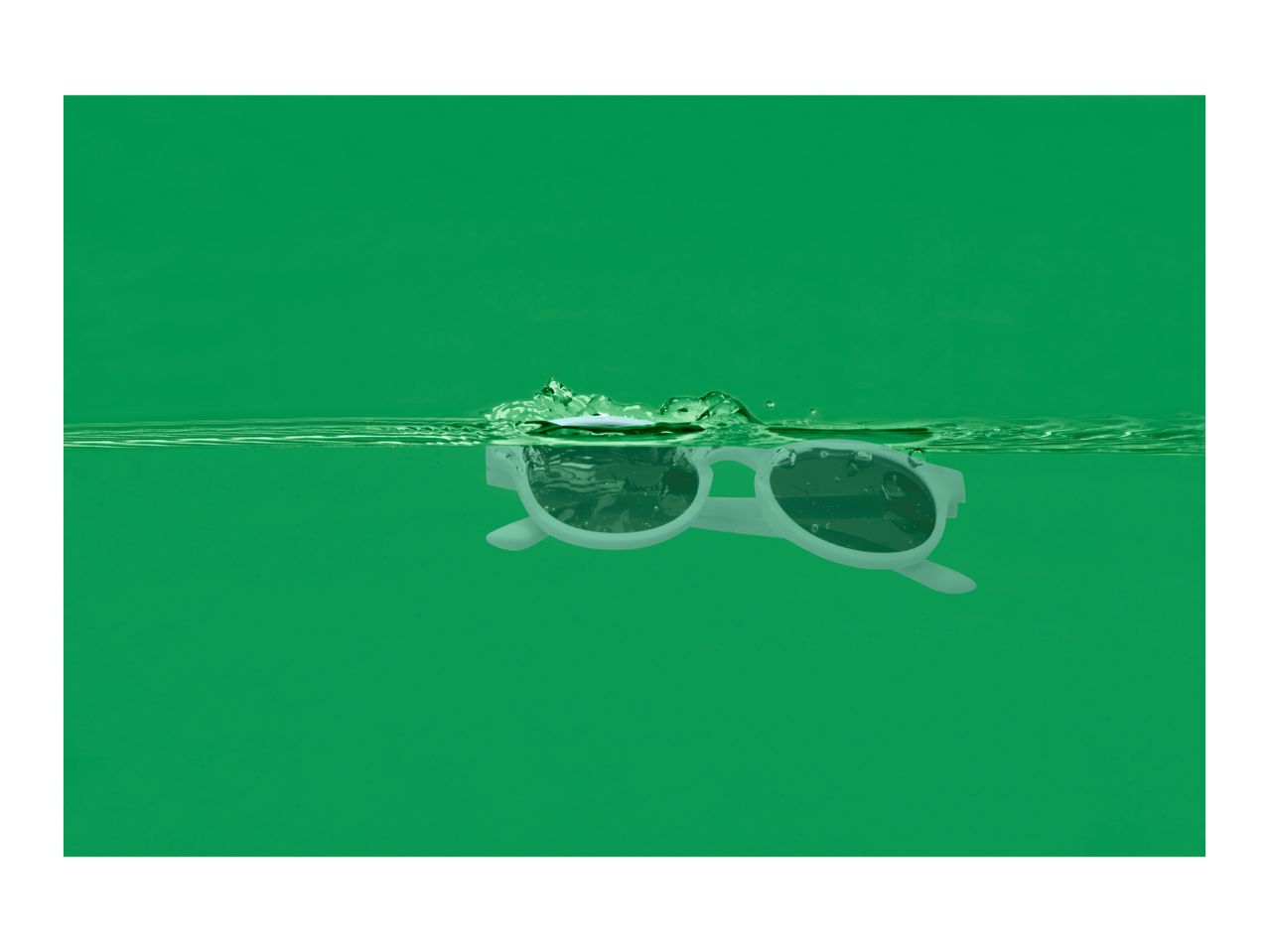 White sunglasses floating in green water with splashes.