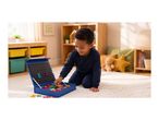 Boy playing with magnetic letters on a portable chalkboard in a bright room.