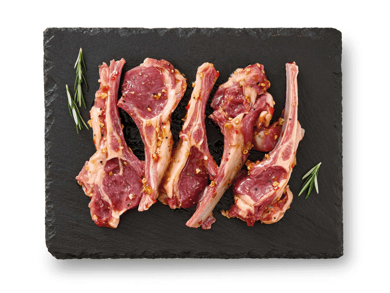 Marineeritud lambakarbonaad rosmariiniga mustal kiltkiviplaadil.