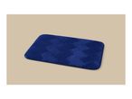 Blue bath mat with a textured herringbone pattern on a beige background.
