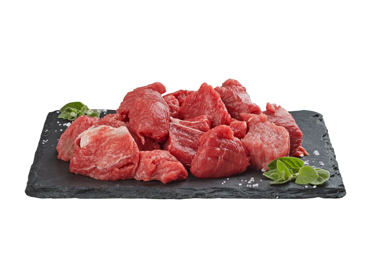 Rohe Fleischwürfel auf schwarzem Schiefer mit Kräutern.