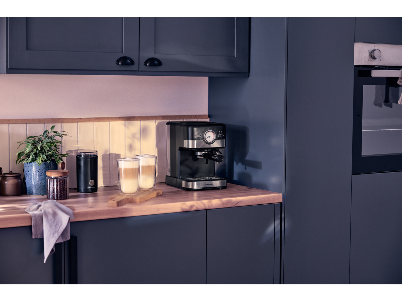Aparat de cafea SILVERCREST și râșniță electrică de cafea într-o bucătărie modernă cu căni de latte.