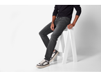Man wearing Esmara men's slim fit jeans, black long-sleeve shirt, and sneakers, sitting on a stool.