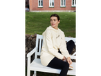 O femeie îmbrăcată într-un hanorac bej și leggings negri stă pe o bancă albă.