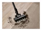 Cordless vacuum cleaner cleaning dirt from a wooden floor and carpet.