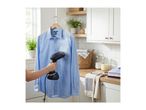 Handheld garment steamer being used on a light blue shirt in a laundry room.