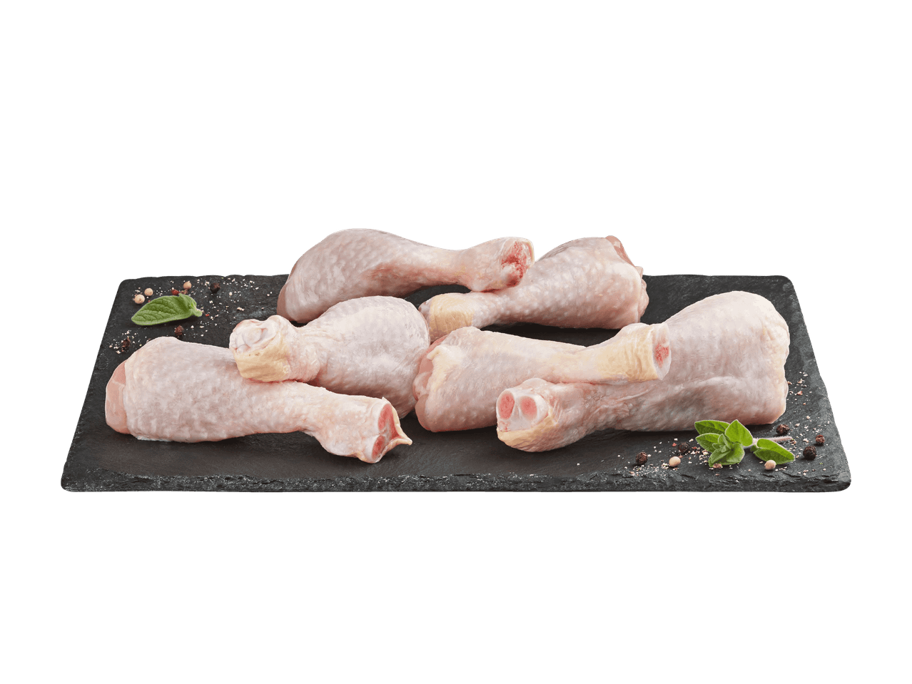 Rohe Hähnchenschenkel auf einem Schieferbrett mit Kräutern und Gewürzen.