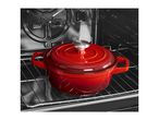 Red cast iron pot with lid inside an oven on a rack.