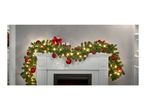 Christmas garland with red baubles and lights draped over a white fireplace mantel.