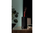 Difuzor de aromă ultrasonic negru, cu abur roșu, lângă o plantă.