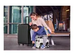 Woman and child with a black suitcase and a panda-themed ride-on suitcase at a station.