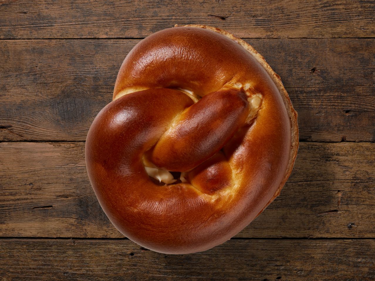 Ein großer, goldbrauner Brezel auf Holz.