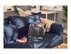 Grey knitting bag filled with yarn and accessories on a blue sofa.