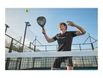 Man in black sportswear playing padel, holding a racket, with a tennis ball in the air.