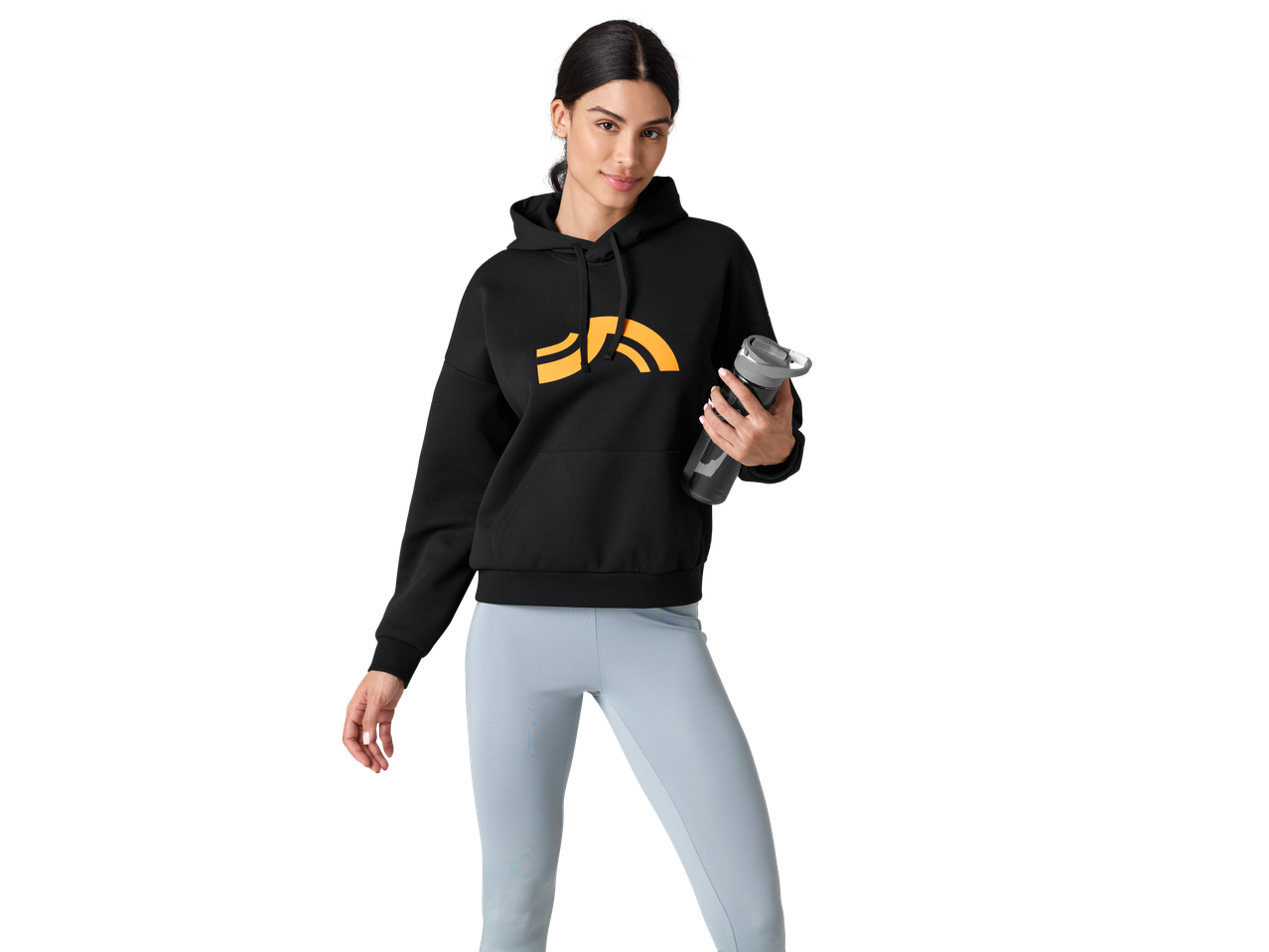 Naine mustas CRIVIT kapuutsiga pusas ja sinistel retuusidel, hoides veepudelit.