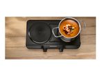Overhead view of a black double hot plate with a pot of seafood soup on the right burner.