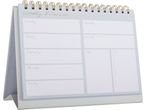 A gray desk calendar with a spiral binding and blank weekly planner pages.