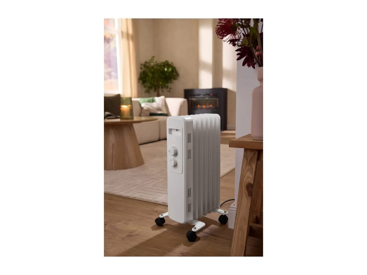 White oil-filled radiator on wheels in a cozy living room setting.