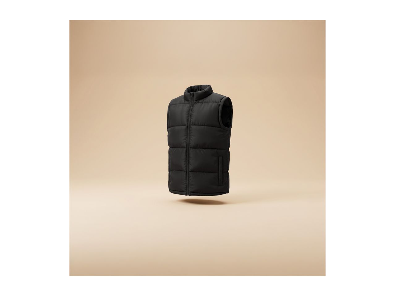 A black puffer vest floating against a beige background.