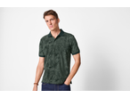 Man wearing a dark green polo shirt with a tropical leaf pattern and dark blue jeans.