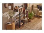 A black metal shoe rack with multiple pairs of shoes and a coat hanging above it in a hallway.