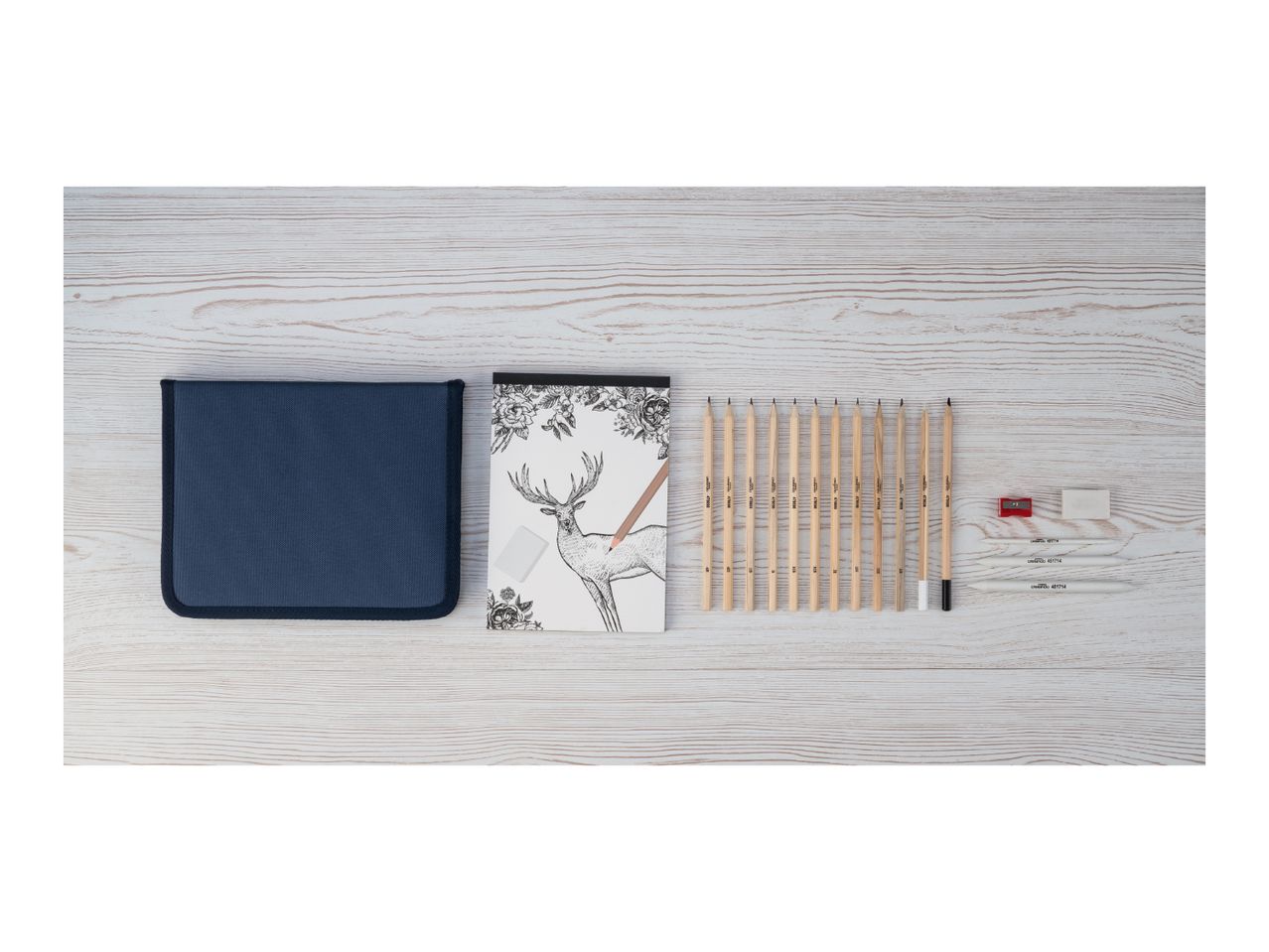 A drawing set with pencils, a sketchbook featuring a deer, a sharpener, erasers, and blending stumps.