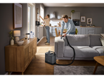 SILVERCREST® 2-in-1 stick vacuum, man cleaning sofa, woman cleaning window.