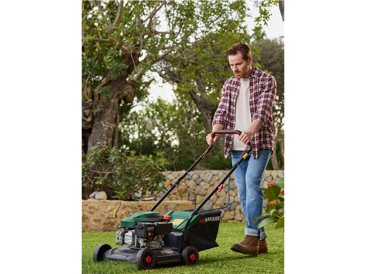 Man using a Parkside lawnmower in a garden.