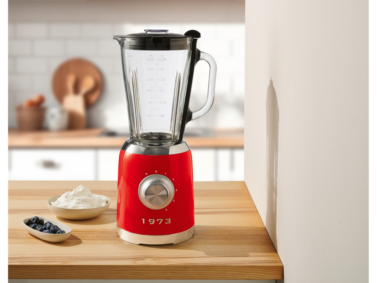 A red retro-style blender with a glass pitcher on a wooden kitchen counter.