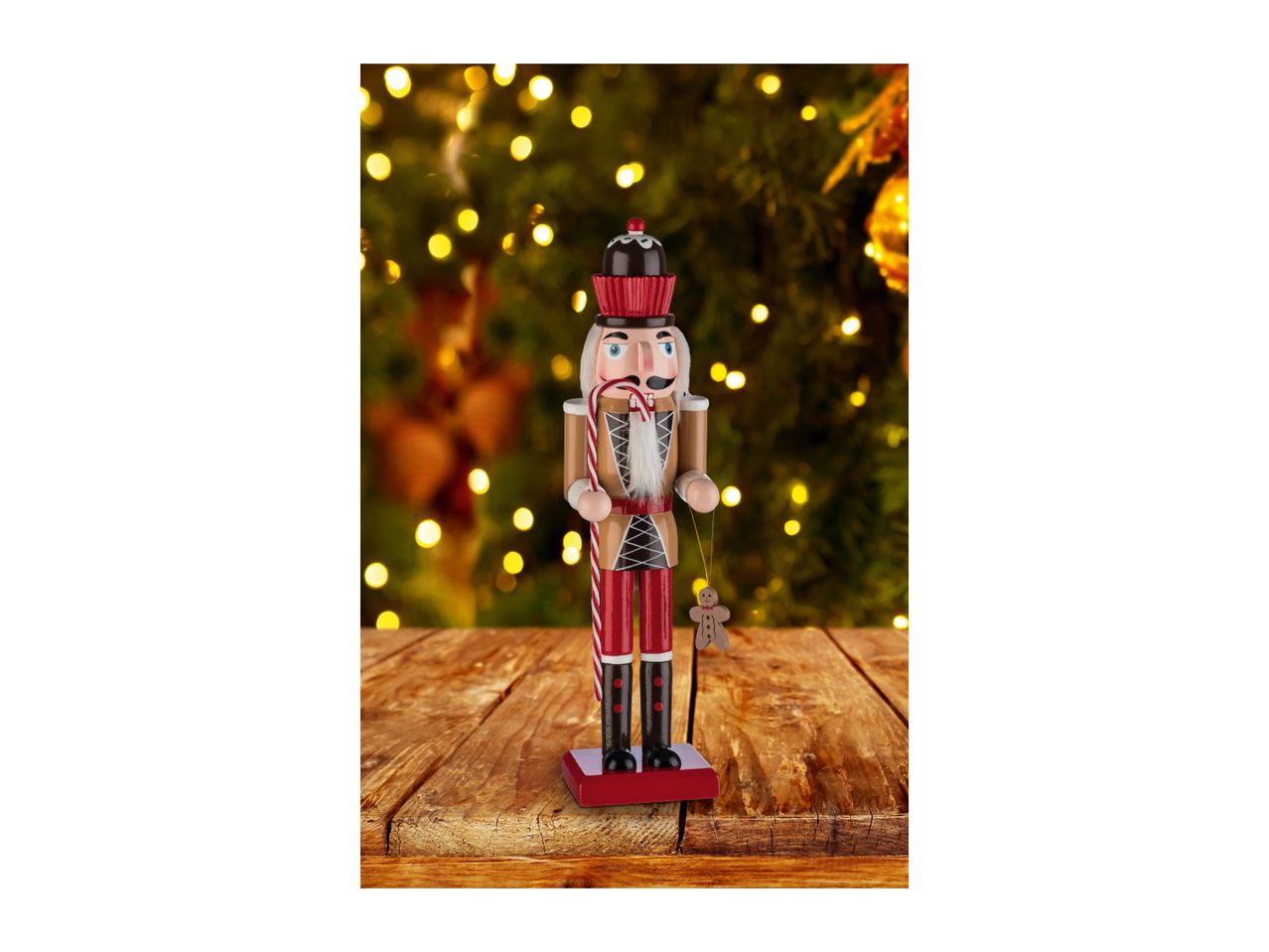 Nutcracker figurine with a candy cane and gingerbread man, on a wooden table with Christmas lights.
