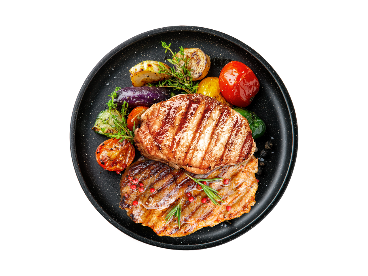 Zwei gegrillte Steaks mit gebratenem Gemüse auf einem schwarzen Teller.