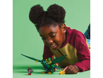Girl playing with a green brick dragon and figures on a green background.