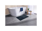 Tappetino da bagno grigio scuro davanti a una vasca da bagno freestanding.