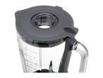 A close-up of a blender jar with a dark gray lid and a clear measuring cup.