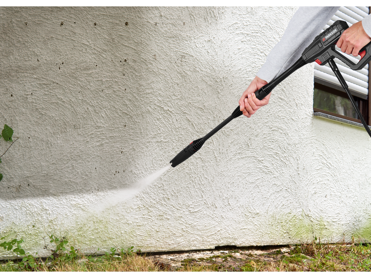 Persoană curățând un perete cu un aparat de spălat cu presiune PARKSIDE.