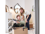 A couple unpacks boxes in their new home, examining a pair of shoes.